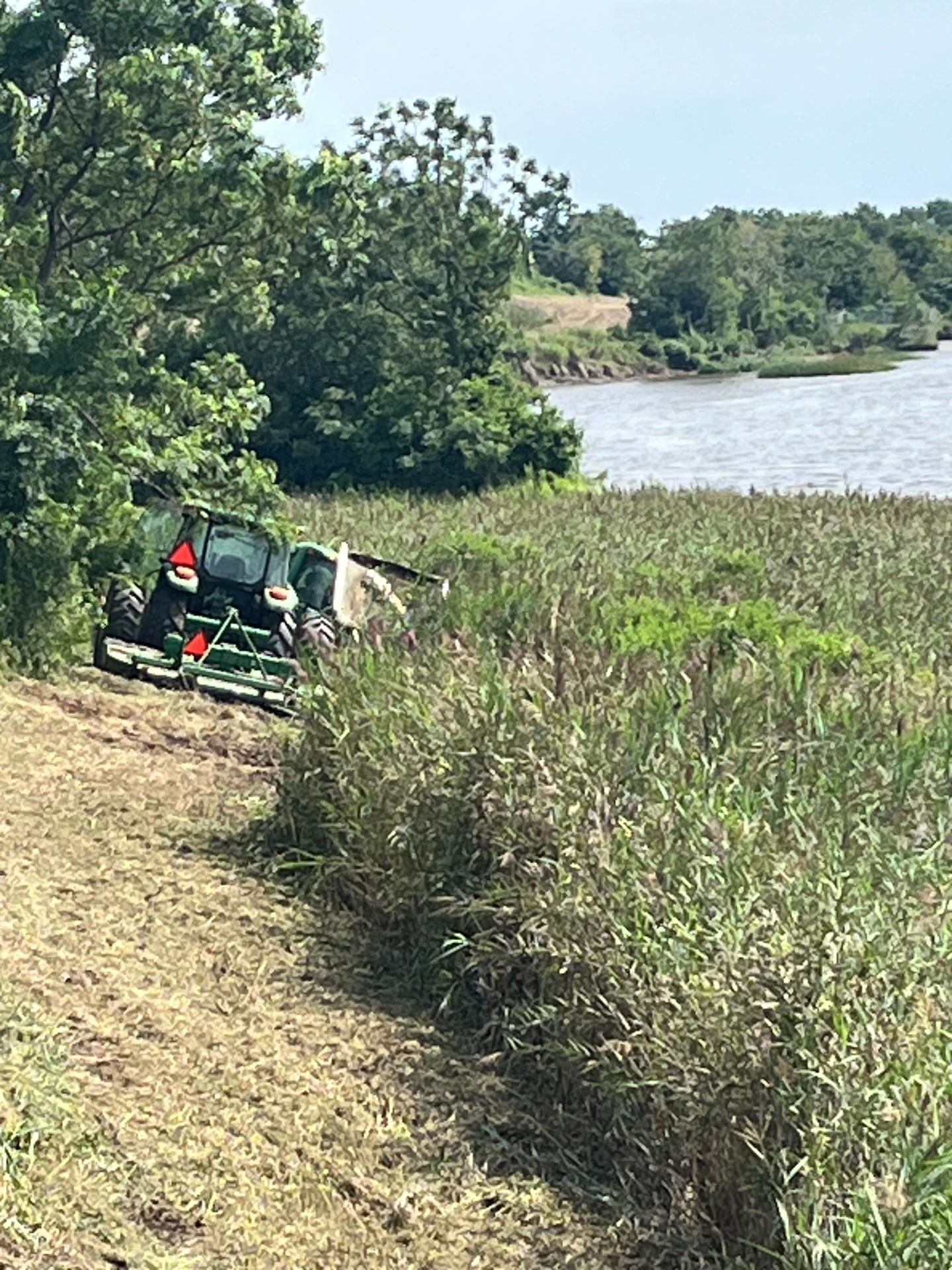 Sam-Jay Services tractor mowing vegetation along a coastal Georgia riverbank